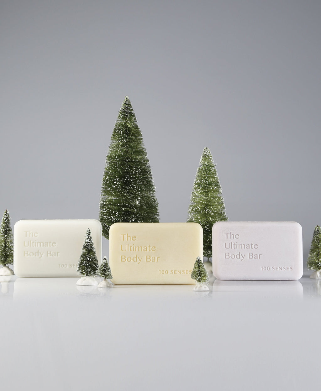 Three Ultimate Body Bars displayed with miniature evergreen trees and faux snow.