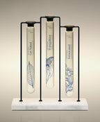 Get Naked, Tranquilizer and Intoxicated Velvet Bath Oils displayed in the Trio Cylinder Soak Stand in black-and-marble.