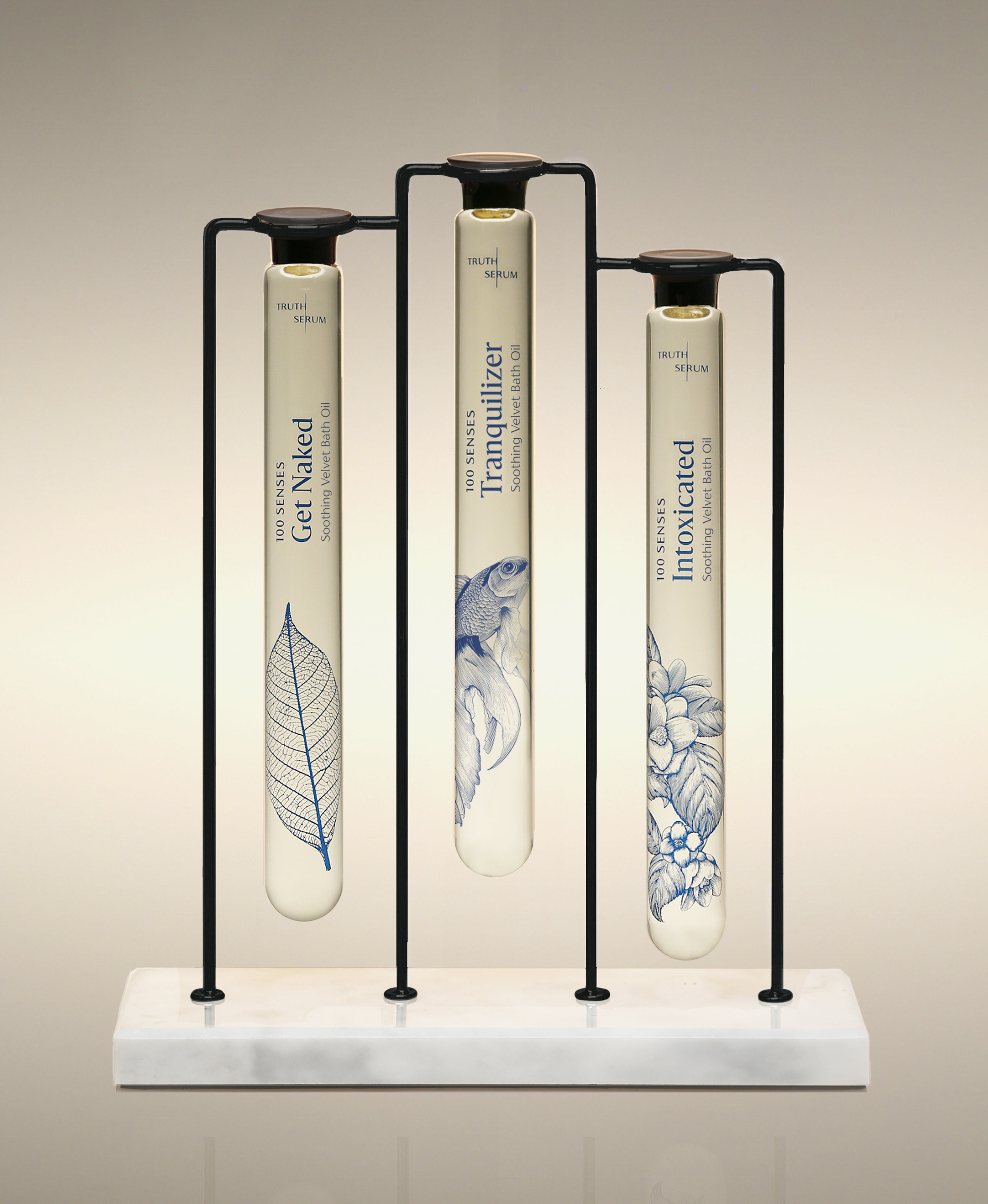 Get Naked, Tranquilizer and Intoxicated Velvet Bath Oils displayed in the Trio Cylinder Soak Stand in black-and-marble.
