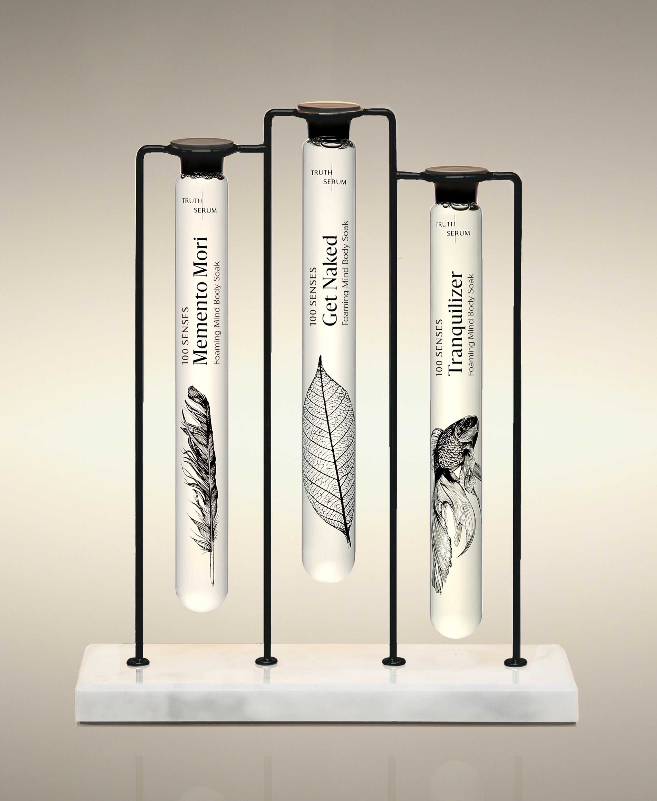 Memento Mori, Get Naked and Tranquilizer glass Foaming Cylinder Soaks displayed in the Trio Cylinder Soak Stand in black-and-marble.