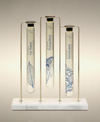 Get Naked, Tranquilizer and Intoxicated Velvet Bath Oils displayed in the Trio Cylinder Soak Stand in gold-and-marble.