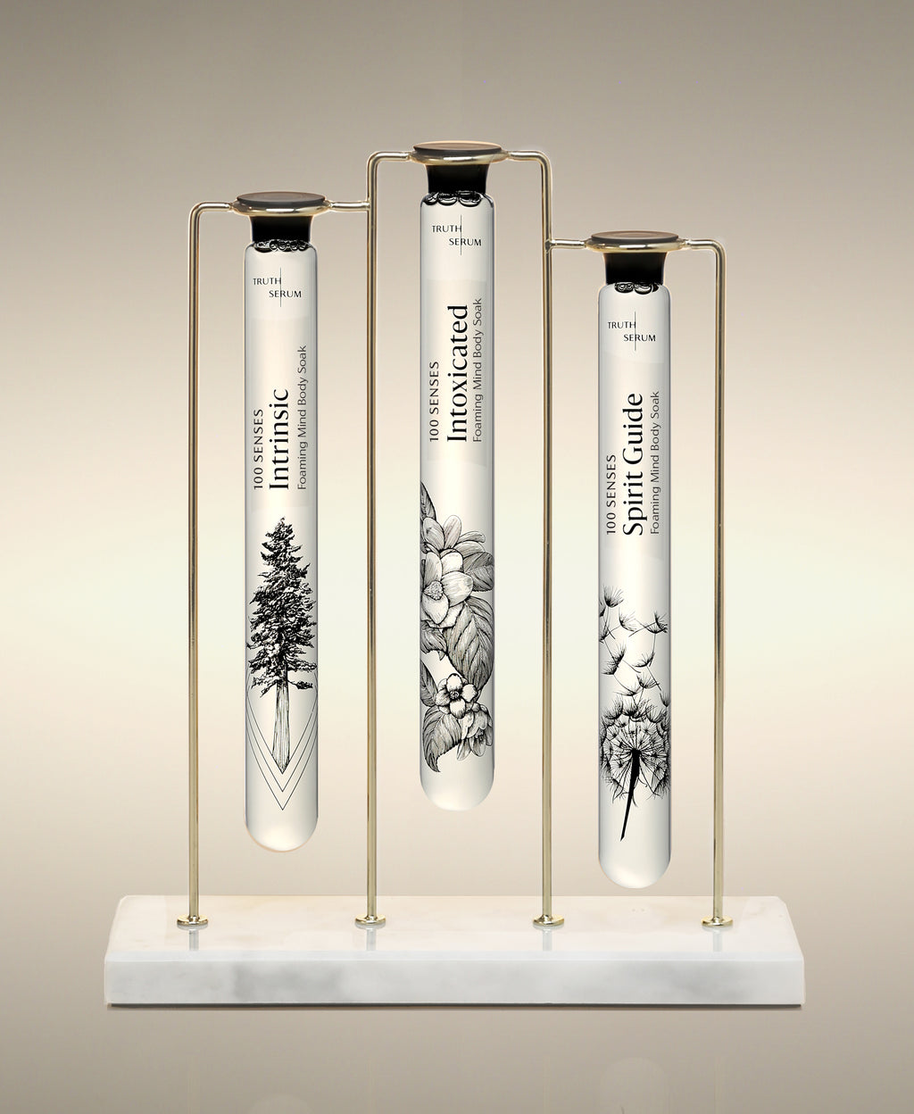 Intrinsic, Intoxicated and Spirit Guide  glass Foaming Cylinder Soaks displayed in the Trio Cylinder Soak Stand in gold-and-marble.