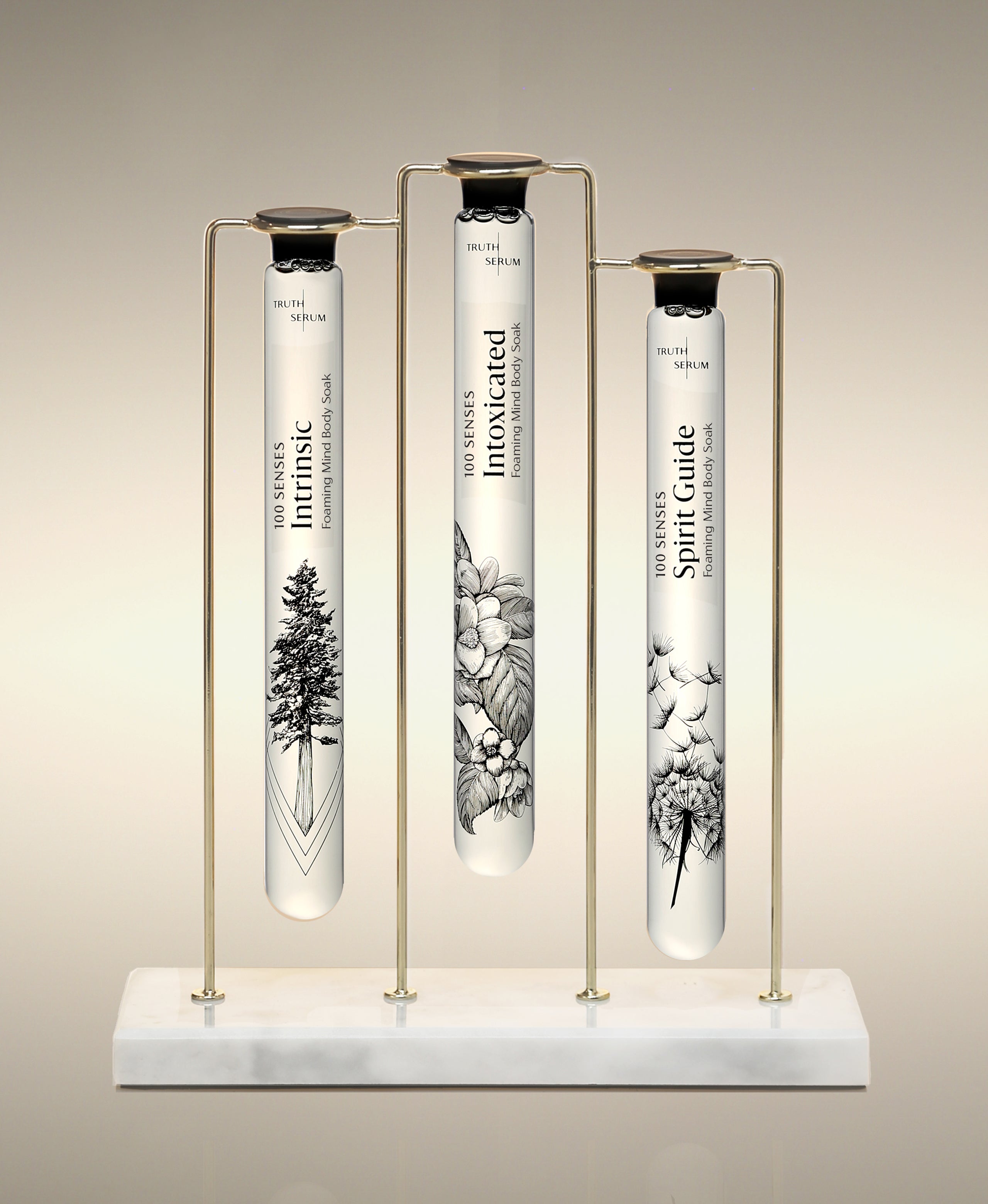Intrinsic, Intoxicated and Spirit Guide  glass Foaming Cylinder Soaks displayed in the Trio Cylinder Soak Stand in gold-and-marble.