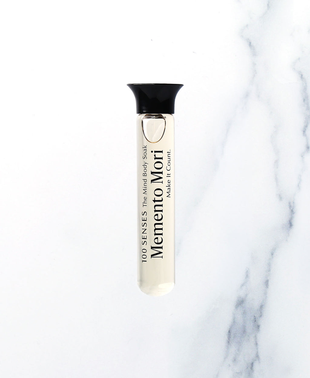 Memento Mori Singular Soak glass vial on white marble.