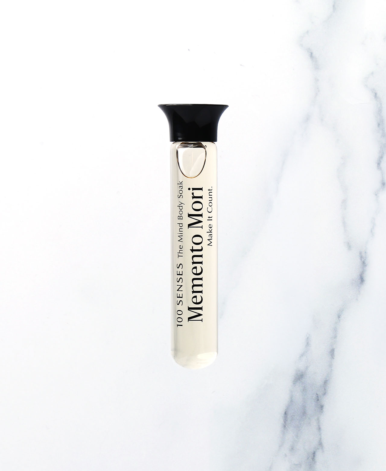 Memento Mori Singular Soak glass vial on white marble.