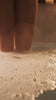 A woman dipping her toe in and out of bubbly water