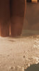A woman dipping her toe in and out of bubbly water
