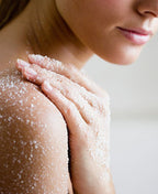 Person smoothing body polish across their shoulder and upper arm.