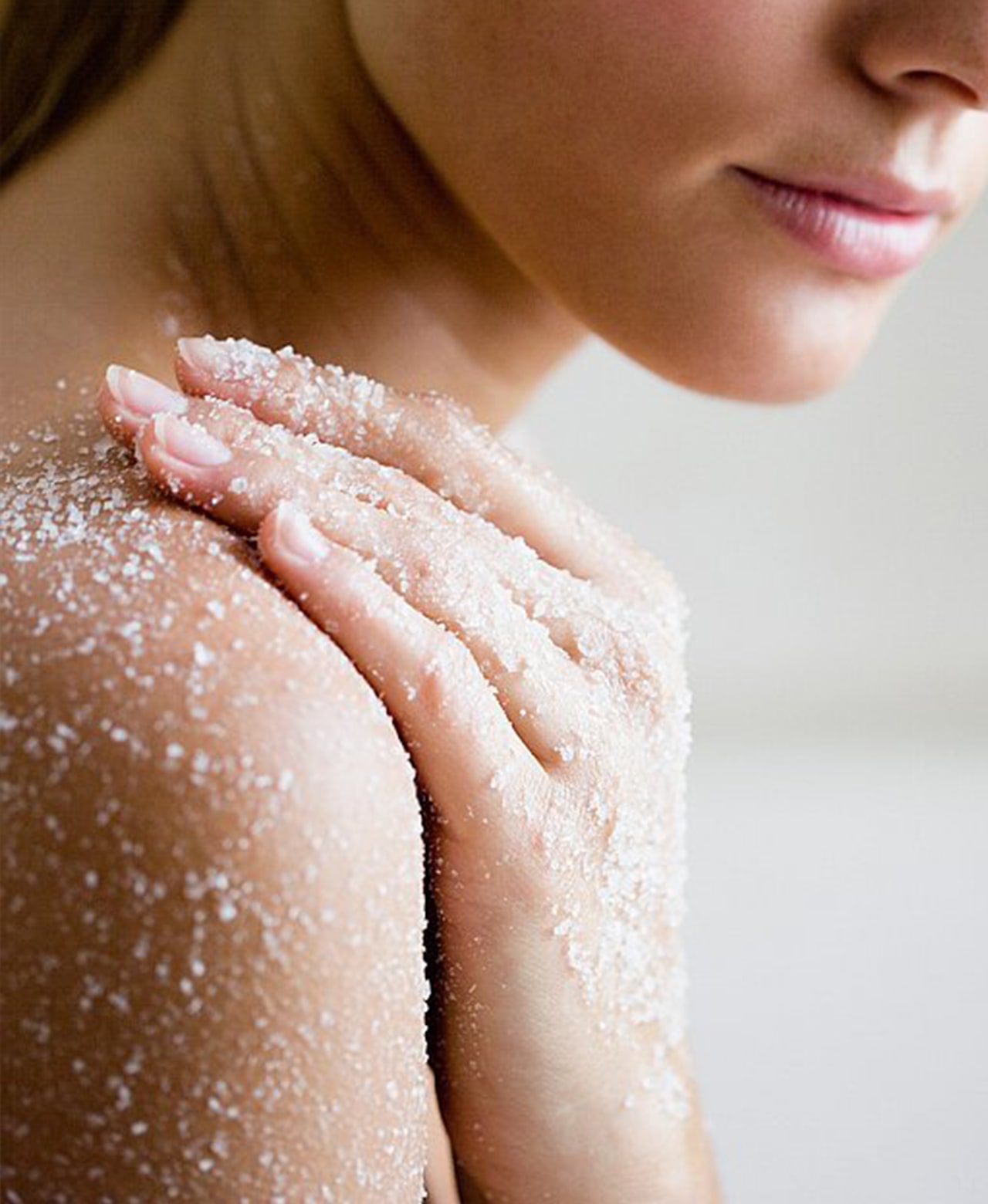 Person smoothing body polish across their shoulder and upper arm.