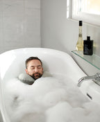 Person reclining in a bubble bath with a gray Head Floater snapped around their neck.