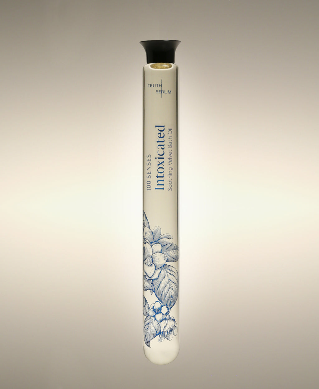 Intoxicated Cylinder Bath Oil glass bottle with a blue floral illustration, standing against a warm neutral background.