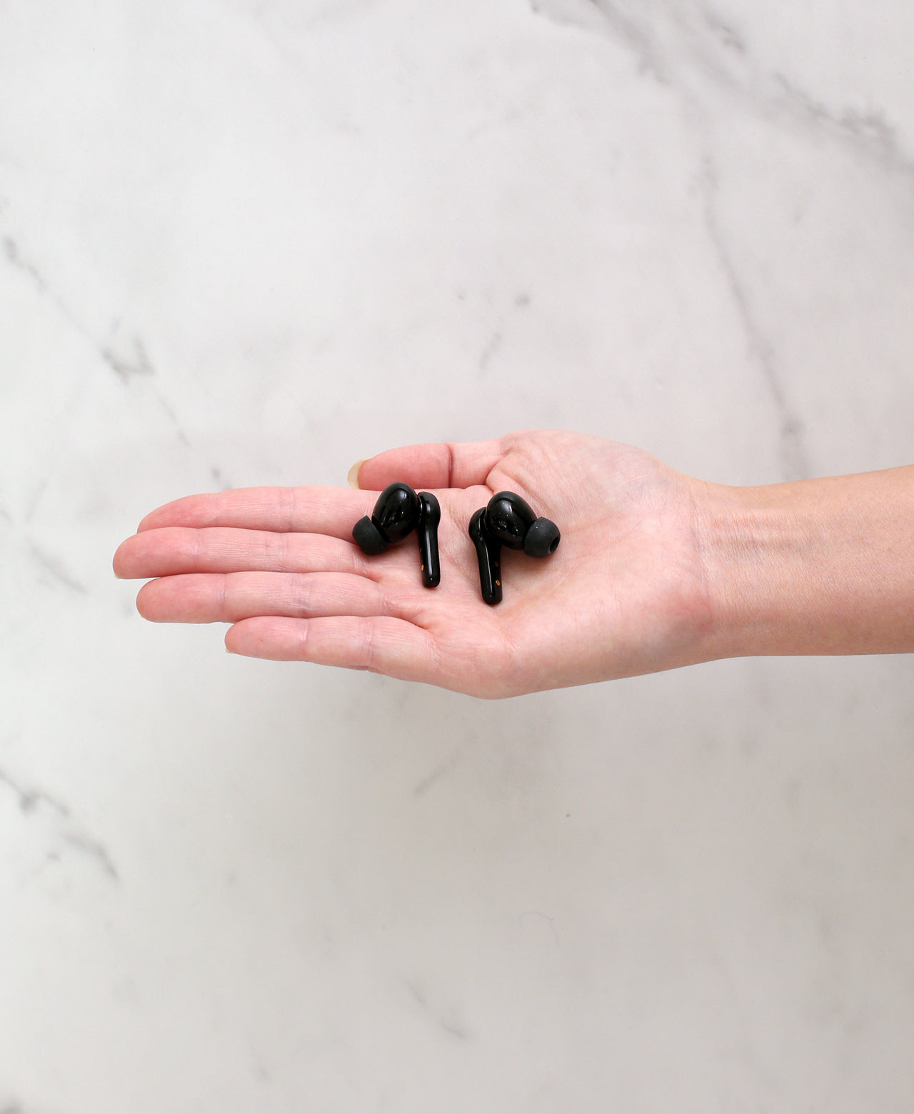 Black BathSonic wireless earbuds resting in an open hand.