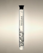 Intoxicated Foaming Bath Soak glass cylinder with a floral illustration, standing against a warm neutral background.
