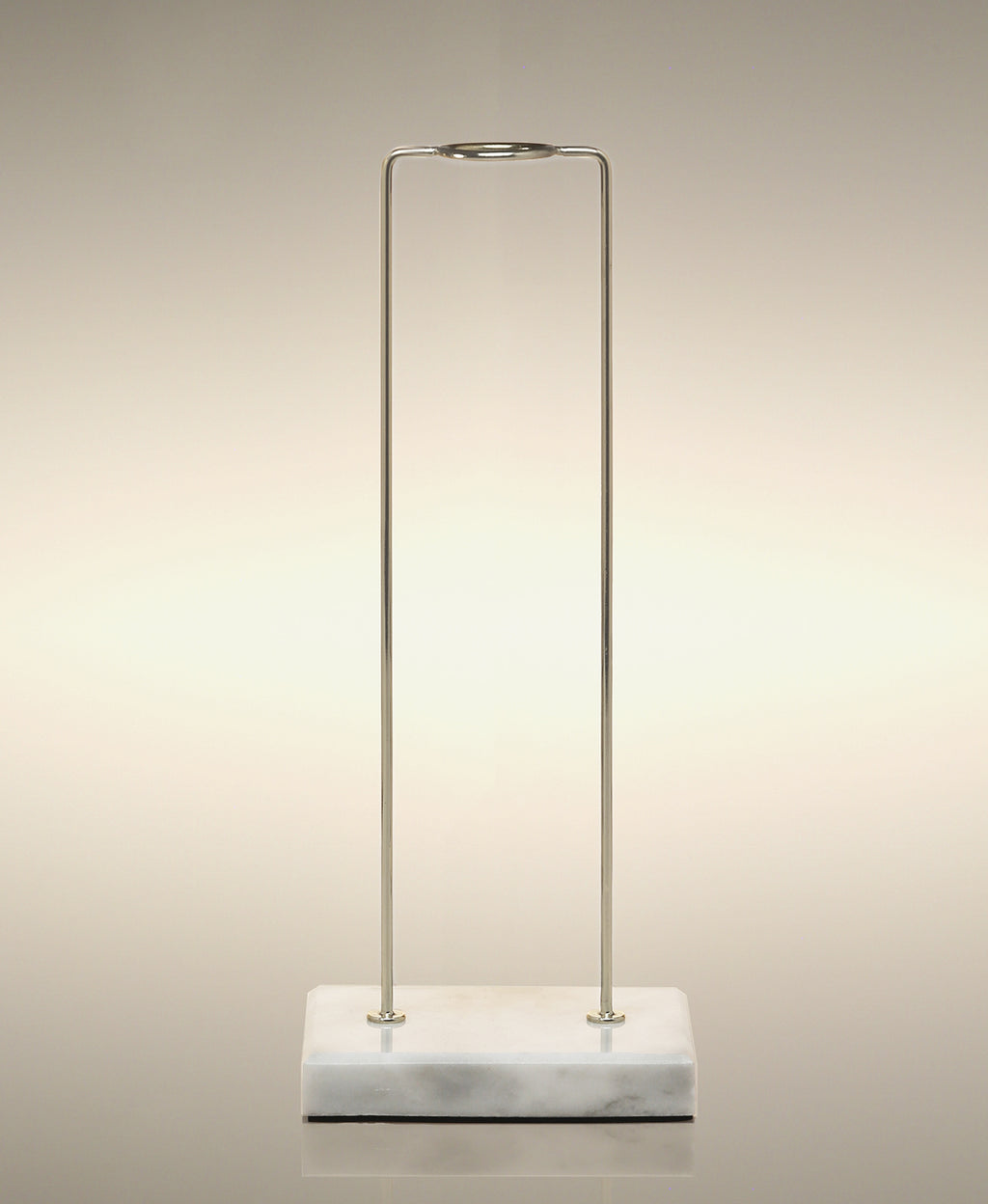 Empty gold metal glass Cylinder Soak stand on a marble base.
