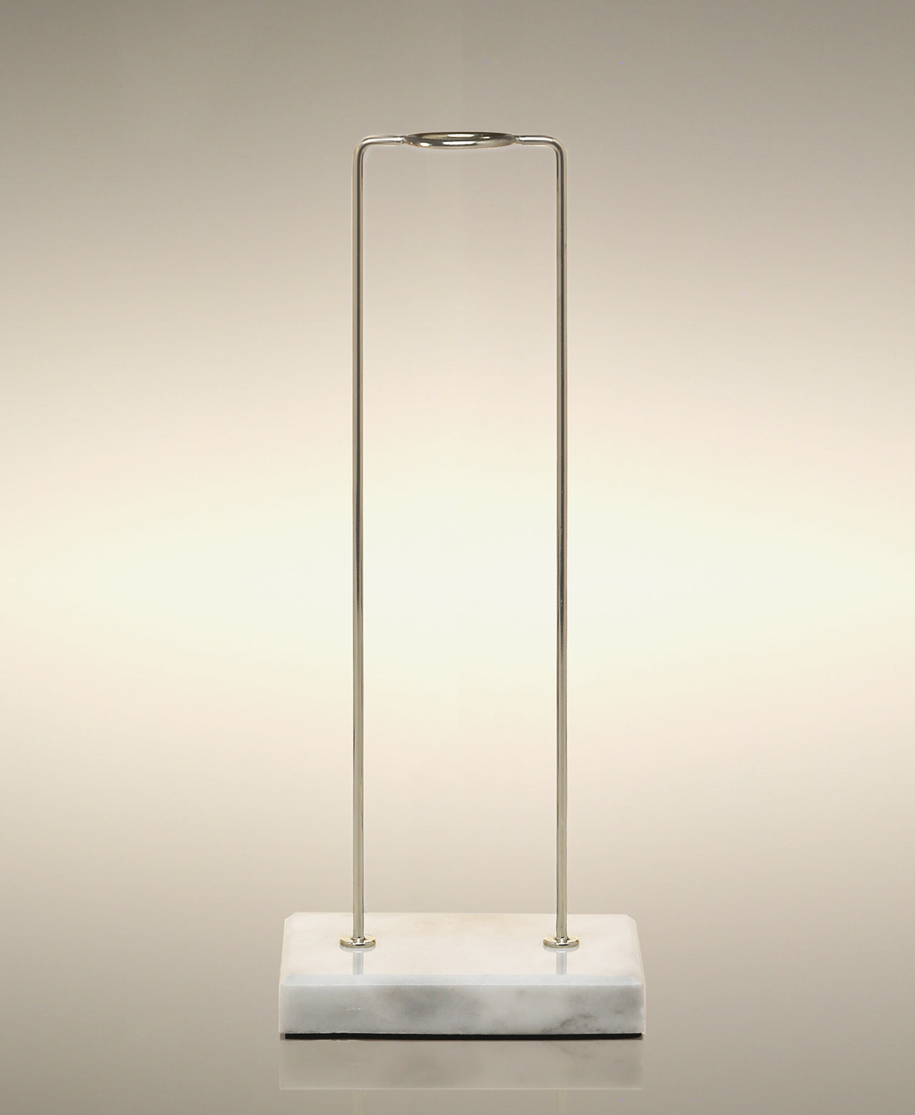 Empty gold metal glass Cylinder Soak stand on a marble base.