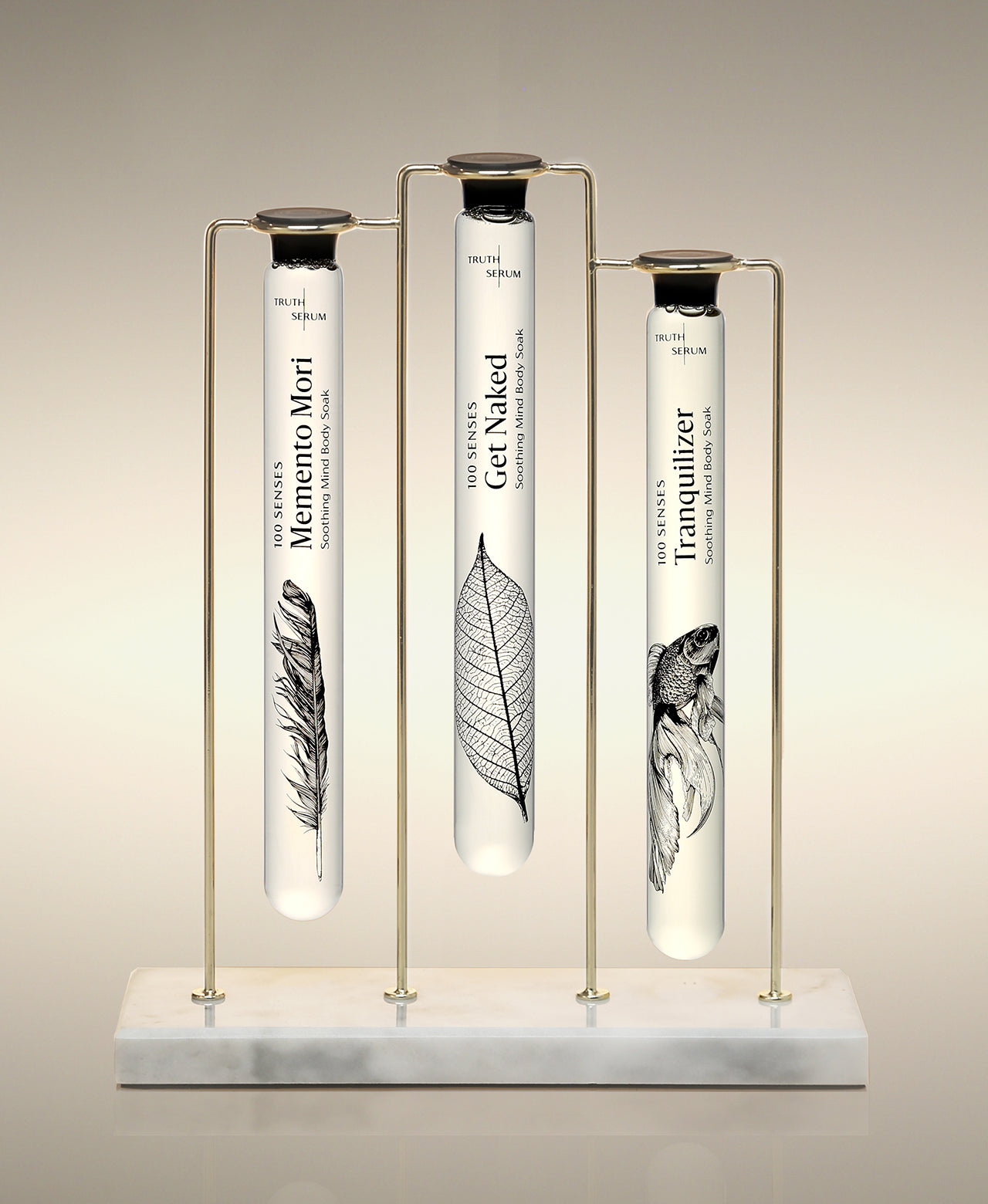 Gold Trio Stand holding Memento Mori, Get Naked and Tranquilizer glass Cylinder Soaks.